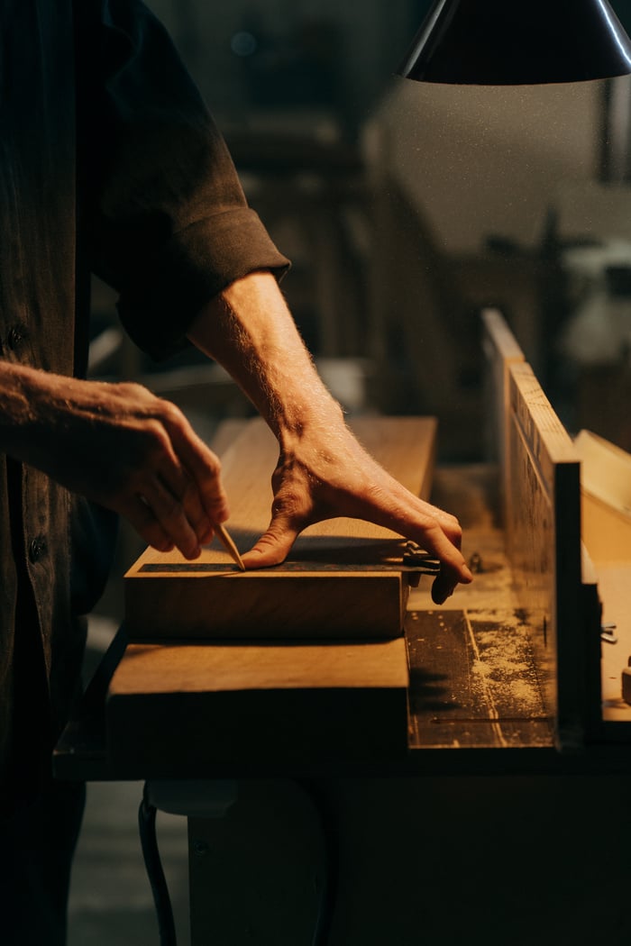 Person in Black T-shirt Holding Brown Wooden Table